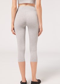 Leggings capri grises fabricados con una tela suave y elástica. Textura suave, cinturilla alta y diseño ajustado. Se llevan zapatos planos negros.