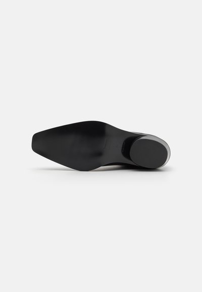 Zapato de tacón alto negro con punta afilada, parte superior de cuero liso y suela de goma sólida. Presenta un tacón redondeado y un diseño minimalista.