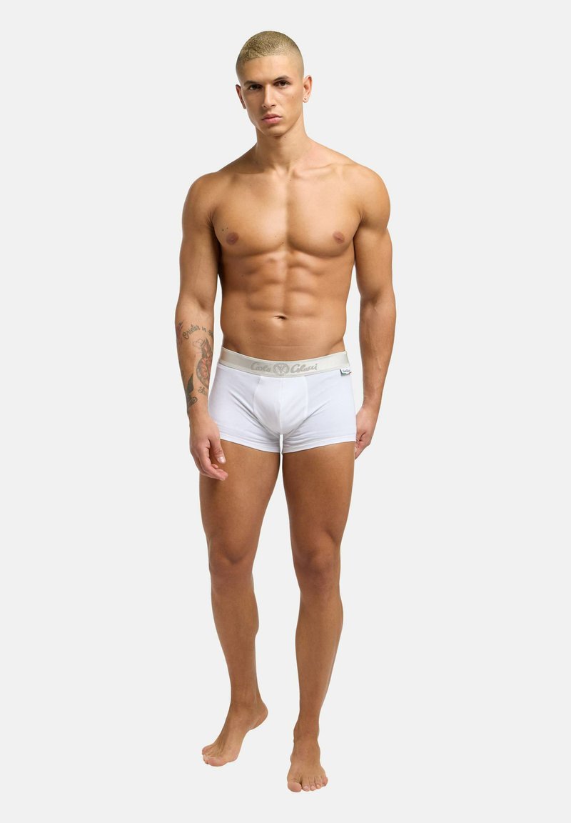 Witte katoenen boxershorts met een grijze tailleband, met een logo aan de voorkant. Het model staat blootsvoets en toont een gespierd lichaam.