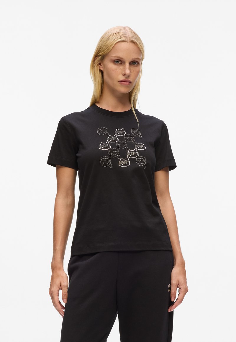 Schwarzes Baumwoll-T-Shirt mit einem grafischen Druck von mehreren Gesichtern in Weiß auf der Vorderseite, kurzen Ärmeln und klassischer Passform.