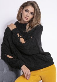 Czarny sweter dzianinowy z warkoczowym wzorem, z szerokimi rękawami z wycięciami. Teksturowana tkanina, luźny krój, żebrowany dekolt i dół.