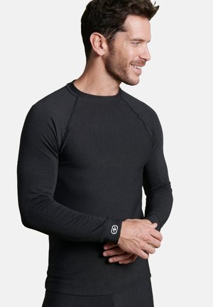 Maglietta nera a maniche lunghe con design aderente, texture a coste e logo a contrasto sul polsino. Presenta maniche raglan per una maggiore libertà di movimento.