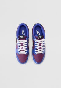 Nike-sneakers med en överdel i lila och blå syntetmaterial, vita snören, svart swoosh-logotyp och perforerade detaljer på tån.