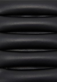 Pelle nera texturizzata disposta in strati di pieghe orizzontali curve, che mettono in mostra una superficie liscia e opaca con sottili motivi di grana.