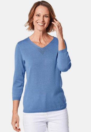 Hellblauer gestrickter Pullover mit V-Ausschnitt und Dreiviertelärmel, der ein dekoratives Ausschnittmuster entlang des Halsauschnitts aufweist.
