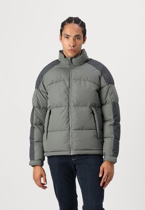 Puffer-Jacke in Grau und Dunkelgrau, mit hohem Kragen, Frontreißverschluss und diagonaler Nahtgestaltung. Weiche, gestepptes Material; zwei Seitentaschen.