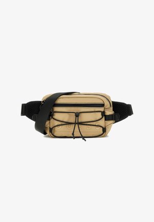 Tan nylon schoudertas met een textuur aan de voorkant, verstelbare zwarte schouderriem, ritscompartimenten en logodetail. Netaccenten op de riem.