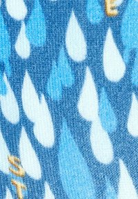 Tissu bleu arborant un motif de gouttes de pluie de tailles et de nuances variées, avec un élément de texte jaune distinct près du bas.