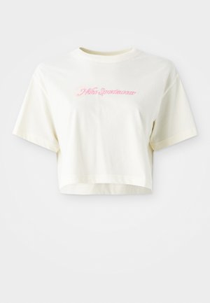 Avkortad, krämfärgad t-shirt i bomull. Har en rosa broderad logotyp som säger "Nike Sportswear." Kortärmad med rund halsringning.