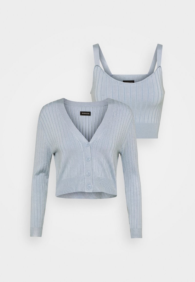 Cardigan court en tricot côtelé bleu clair avec boutons et débardeur court assorti à bretelles, tous deux présentés sur fond blanc.