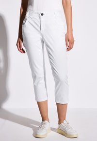 Witte cropped broek gemaakt van lichtgewicht stof, met zijzakken, een knoopsluiting aan de voorkant en een relaxte pasvorm. Gekocht met beige sneakers.