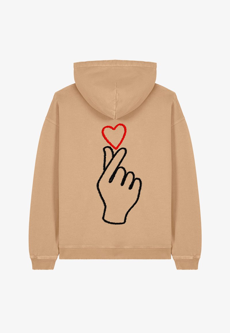 Hoodie beige avec un contour noir d'une main faisant un geste de cœur, accompagné d'un cœur rouge au-dessus des doigts. Tissu doux, coupe décontractée.