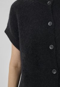Black, textured cardigan with short sleeves and a loose fit, featuring six dark buttons along the front for closure.