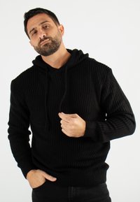 Sweat à capuche noir en tricot avec un motif texturé, doté d'une capuche à cordon de serrage, de manches longues et de poignets et ourlet côtelés.