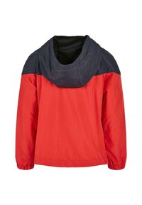 Veste coupe-vent rouge et marine, dotée d'une capuche, de poignets élastiques et d'un tissu léger. Design simple avec un bloc de couleur.