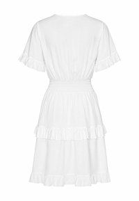 Robe blanche à manches courtes avec taille élastique et volants superposés sur les manches et l'ourlet, vue de dos sur un fond uni.