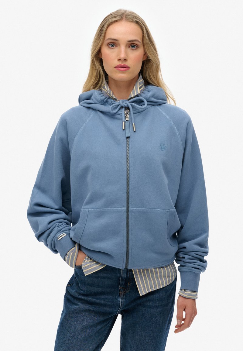Blauwe rits hoodie gemaakt van zachte fleece, met een capuchon met trekkoord, voorzakken, ribgebreide manchetten en een lichtgestreept shirt eronder.