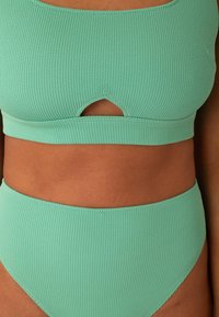 Set di bikini a coste verde menta con top corto caratterizzato da un dettaglio a taglio. Il fondo a vita alta completa il design del top.