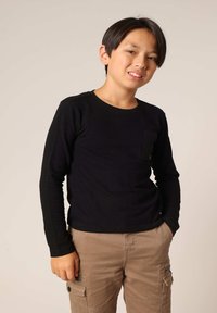 Zwart langslijfshirt met een ronde halslijn en een borstzak, gecombineerd met beige cargobroeken met zijritsen en zakken.