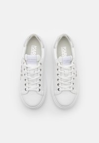 Białe trampki z gładką skórzaną cholewką, okrągłym noskiem i płaskim sznurowanym designem. Srebrne akcenty na języku i boku.