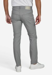 Grijze slim-fit broeken van lichtgewicht stof, met een zachte textuur, achterzakken met afgeronde kleppen en een subtiele merketiket op de tailleband.