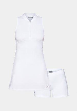 Hvid ærmeløs kjole med frontlynlås, der har en tætsiddende overdel og en flagrende nederdel, parret med matchende hvide shorts.