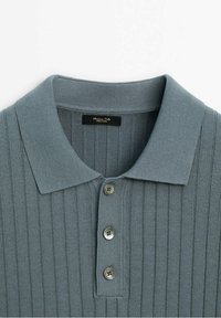 Polo gris côtelé avec col, patte à trois boutons et tissu texturé. Étiquette indiquant "Massimo Dutti, Fabriqué en Italie."