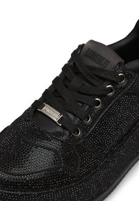 Sneakers neri con superficie texturizzata e piccoli rivetti, design con lacci e una placca con il logo sulla linguetta. Suola in gomma con occhielli in metallo.