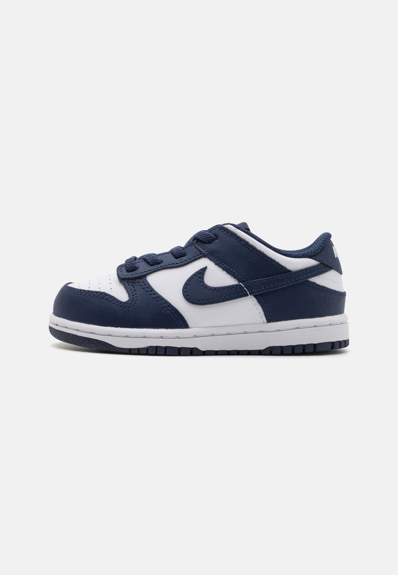 Ténis Nike com uma combinação de cores azul-marinho e branca, material de couro liso, design com atacadores e sola de borracha com textura para tração.