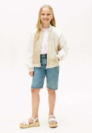 Beige en witte bomberjack, roze t-shirt, denim shorts en witte sandalen met plateausole. Glad materiaal en casual ontwerp.