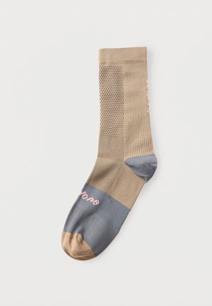 Calzino beige e grigio con motivi testurizzati e testo rosa pallido sul piede, mostrato disteso su sfondo bianco.