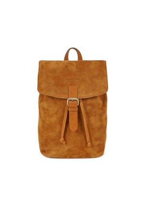 Tan suede backpack with a fold-over flap, drawstring closure, and a top handle. Features branding detail on the front. Soft texture.