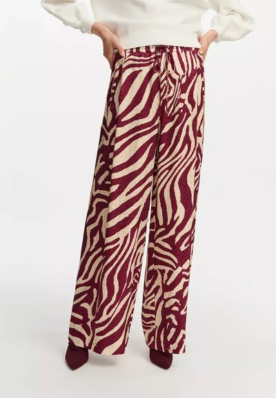 Pantalones de pierna ancha en un patrón de cebra marrón y beige, con cintura elástica y cierre de cordón. Fabricados con tela texturizada.