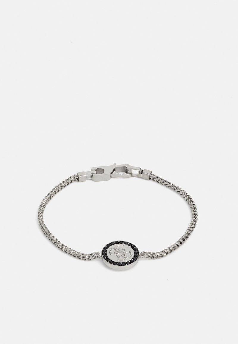 Hõbedane kettkäevõru, mille keskel on logo sisaldav medallion, ümbritsetud musta kivi aktsendiga. Tekstureeritud lingid lisavad detailsust.