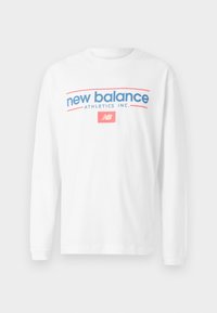Hvit langermet t-skjorte laget av bomull; har teksten "new balance" og "ATHLETICS INC." i blå og rosa, med logoen på forsiden.