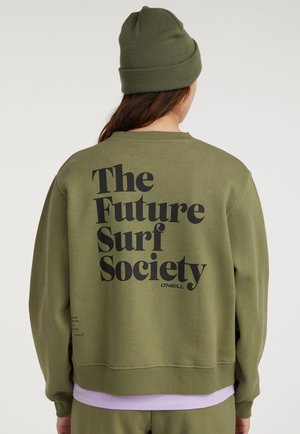 Person trägt eine olivgrüne Mütze und einen passenden Pullover mit fettem schwarzen Text „The Future Surf Society“ auf dem Rücken.