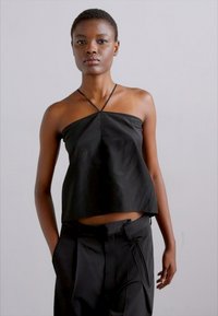 Black sleeveless top with a loose fit, made of lightweight fabric, featuring symmetrical cross straps and a straight hemline.