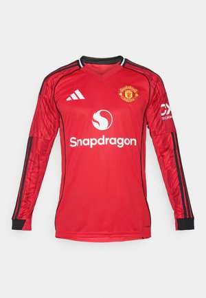 Červený dlhý rukáv futbalový dres s čiernymi detailmi, dizajn s v-čelom, logo Adidas, erb Manchester United a text "Snapdragon" na prednej strane.