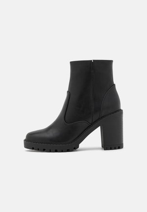 Bottes noires pour cheville en cuir lisse avec un talon bloc, des panneaux latéraux élastiques et une semelle en caoutchouc texturée pour une meilleure adhérence.