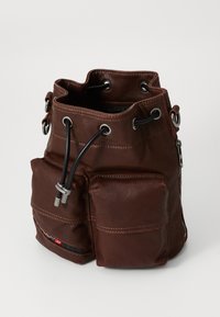 Brown leather bucket bag with drawstring closure, featuring a front pocket and silver hardware detailing. Smooth texture with visible seams.