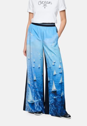 Wide-leg pants with blue ocean and white sailboats print, paired with a white t-shirt featuring "Ocean Love" text and anchor graphic.