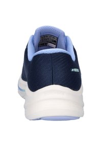 Marineblauwe mesh sneaker met een lichte blauwe kraag en een zachte witte zool. Het toont het "SKECHERS"-logo aan de zijkant en het productlabel binnenin de schoen.