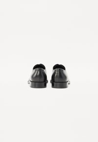 Scarpe in pelle nera con finitura liscia, punta rotonda e tacco basso. Design minimalista senza motivi visibili o dettagli in metallo.