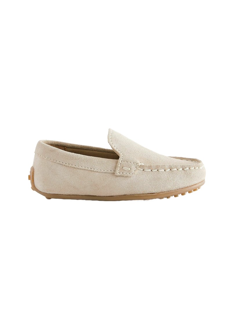 Chaussure slip-on en daim beige avec une texture lisse, des coutures de mocassin et une semelle en caoutchouc dotée de petits points de traction. Design minimaliste.