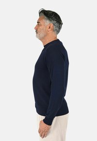 Maglione a maniche lunghe di colore blu navy con design aderente, caratterizzato da polsini e fondo a coste, realizzato in un tessuto a maglia testurizzato. Viene mostrato in vista laterale.