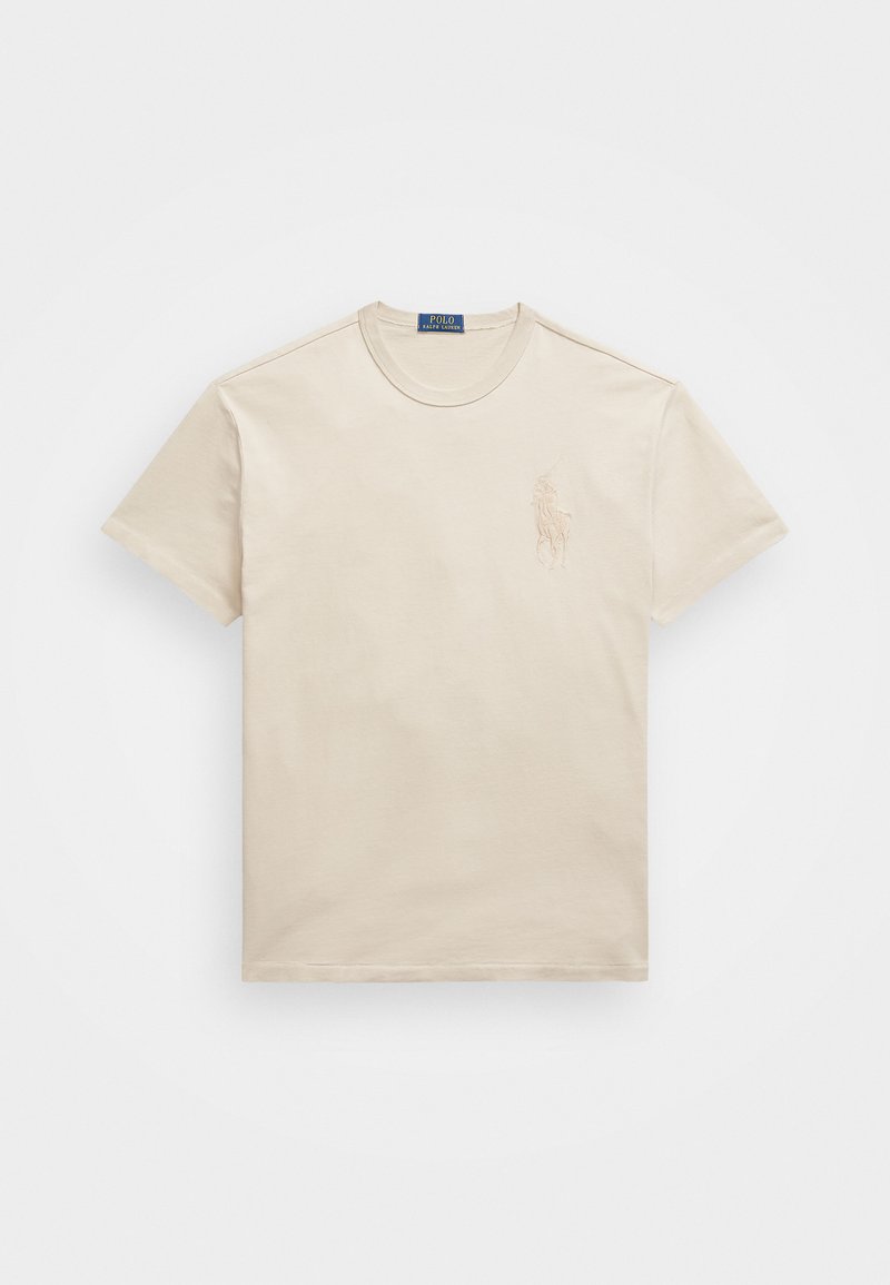 Beige bomull t-shirt med rund hals, korta ärmar och en diskret broderad logotyp på vänster bröst. Slät textur, avslappnad passform.