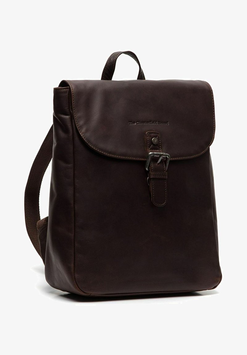 Mochila de cuero marrón con cierre de solapa, hebilla de metal y correas de tela ajustables; textura suave con branding en relieve en la parte frontal.