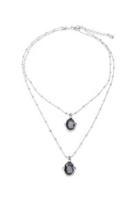 Collar de plata de varias capas con dos colgantes ovalados de piedras preciosas oscuras con acabado facetado, conectados por cadenas delicadas.