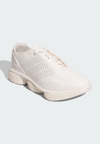 Basket de sport blanche avec un dessus perforé pour la respirabilité, en matériau synthétique lisse, semelle ronde et détail de rembourrage texturé.