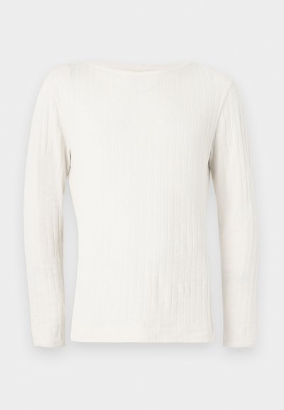 Λευκό ριμπ πλεκτό πουλόβερ με μακριά μανίκια και στρογγυλή λαιμόκοψη, απλωμένο σε επίπεδη επιφάνεια πάνω σε ανοιχτό γκρι φόντο.